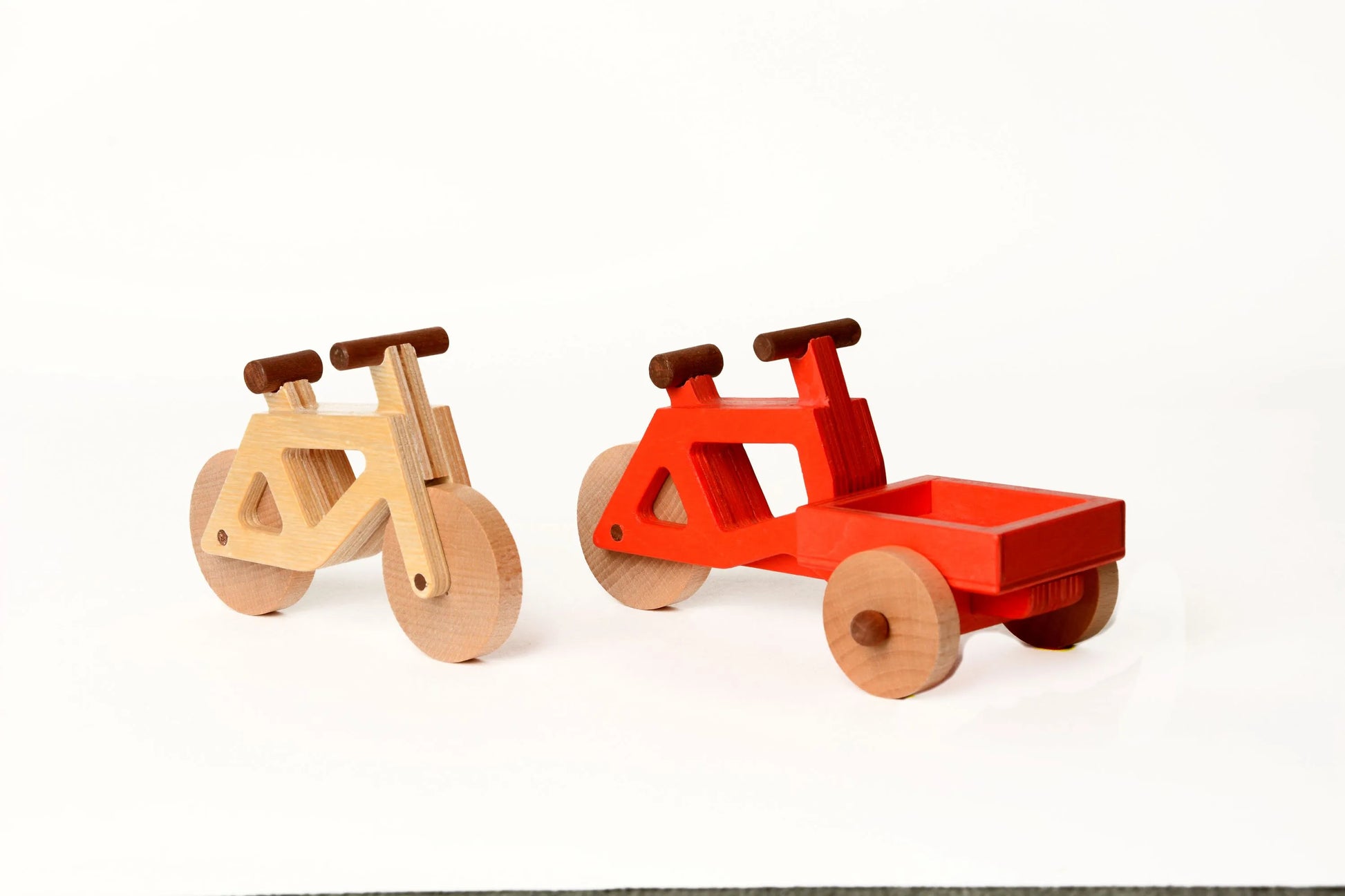 Das Spielzeugfahrrad aus Holz in natur und das Lastenrad von Spielwende in rot