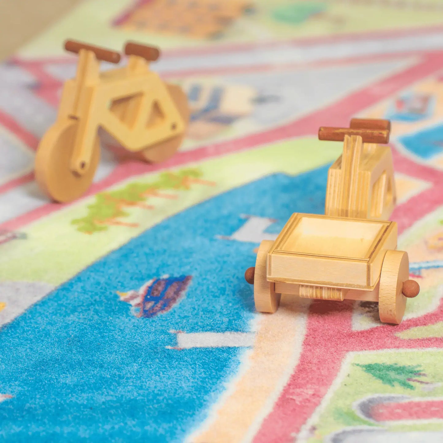 Ein Spielzeug-Lastenrad und ein Spielzeugfahrrad in natur stehen auf dem Spielteppich von Spielwende auf Radwegen.