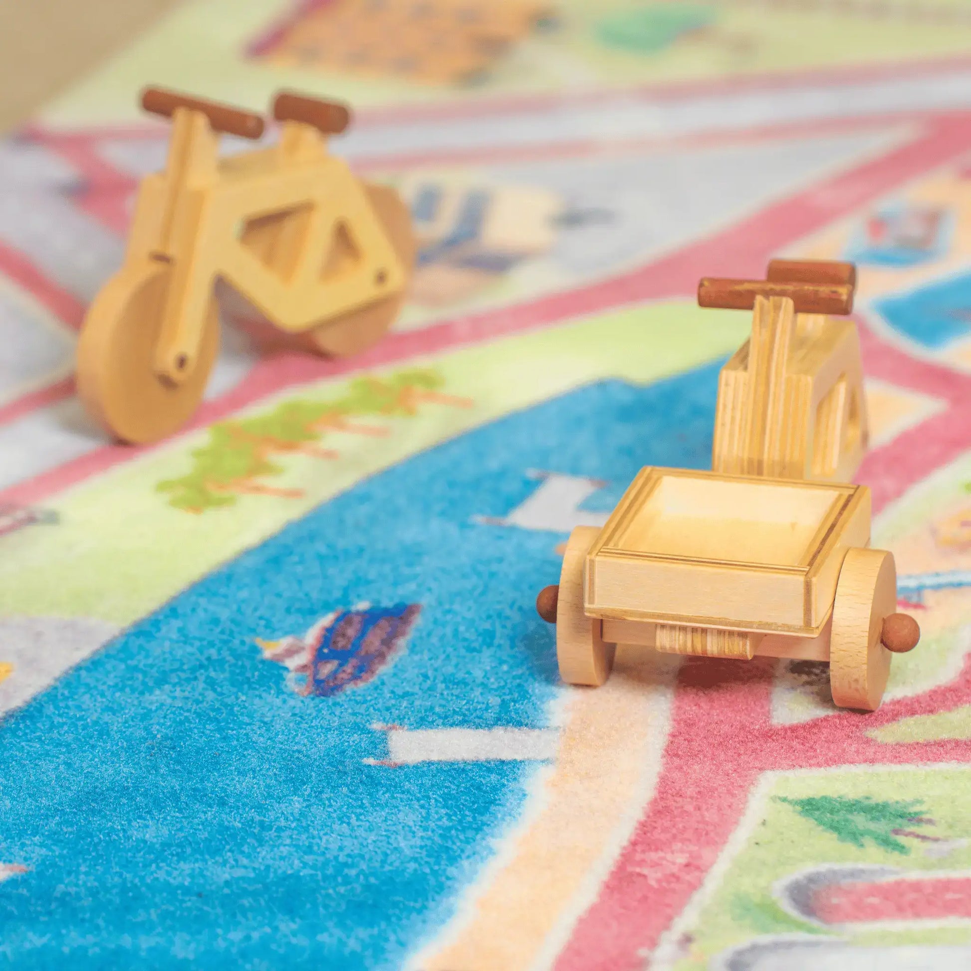 Ein Spielzeug-Lastenrad und ein Spielzeugfahrrad in natur stehen auf dem Spielteppich von Spielwende auf Radwegen.