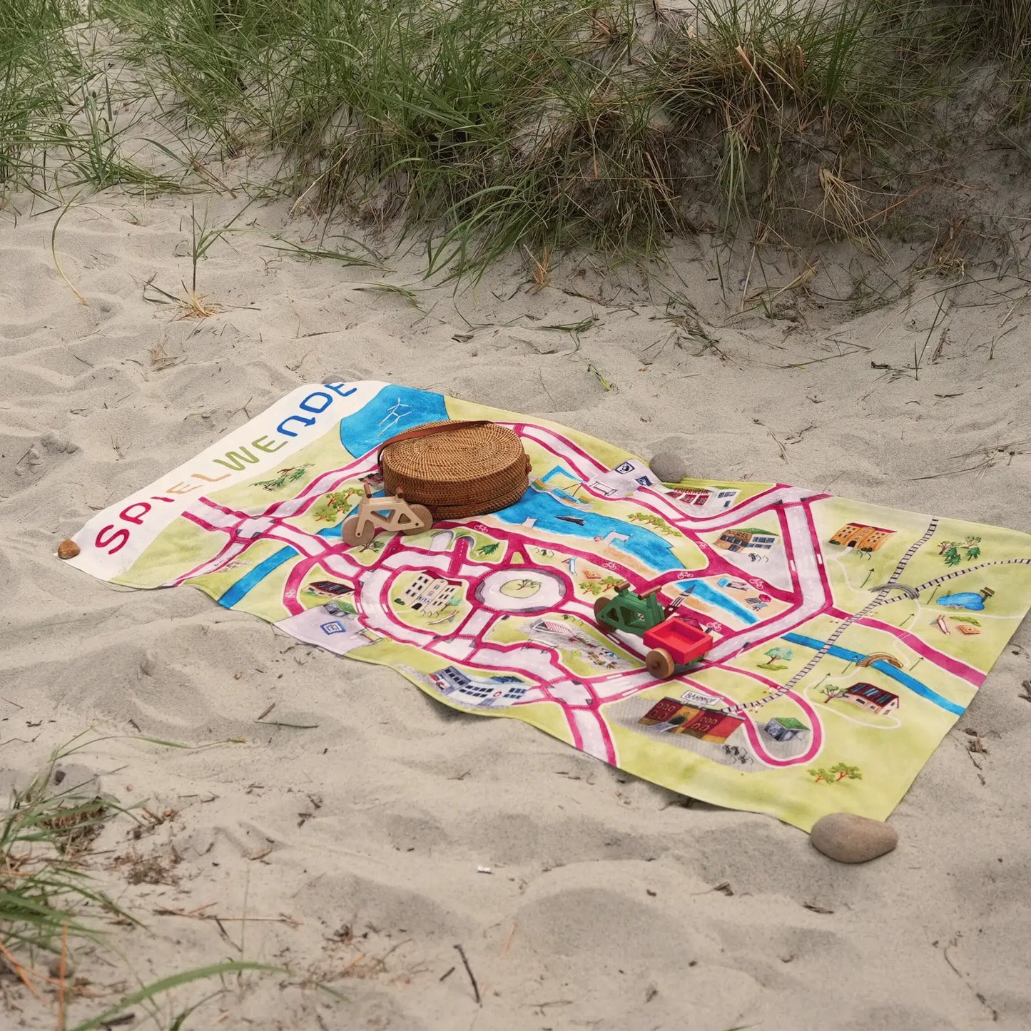 Strandhandtuch 'Stadt von Morgen' 140x70cm, farbenfrohes Design mit nachhaltigen Stadtmotiven, liegt auf dem Strand.