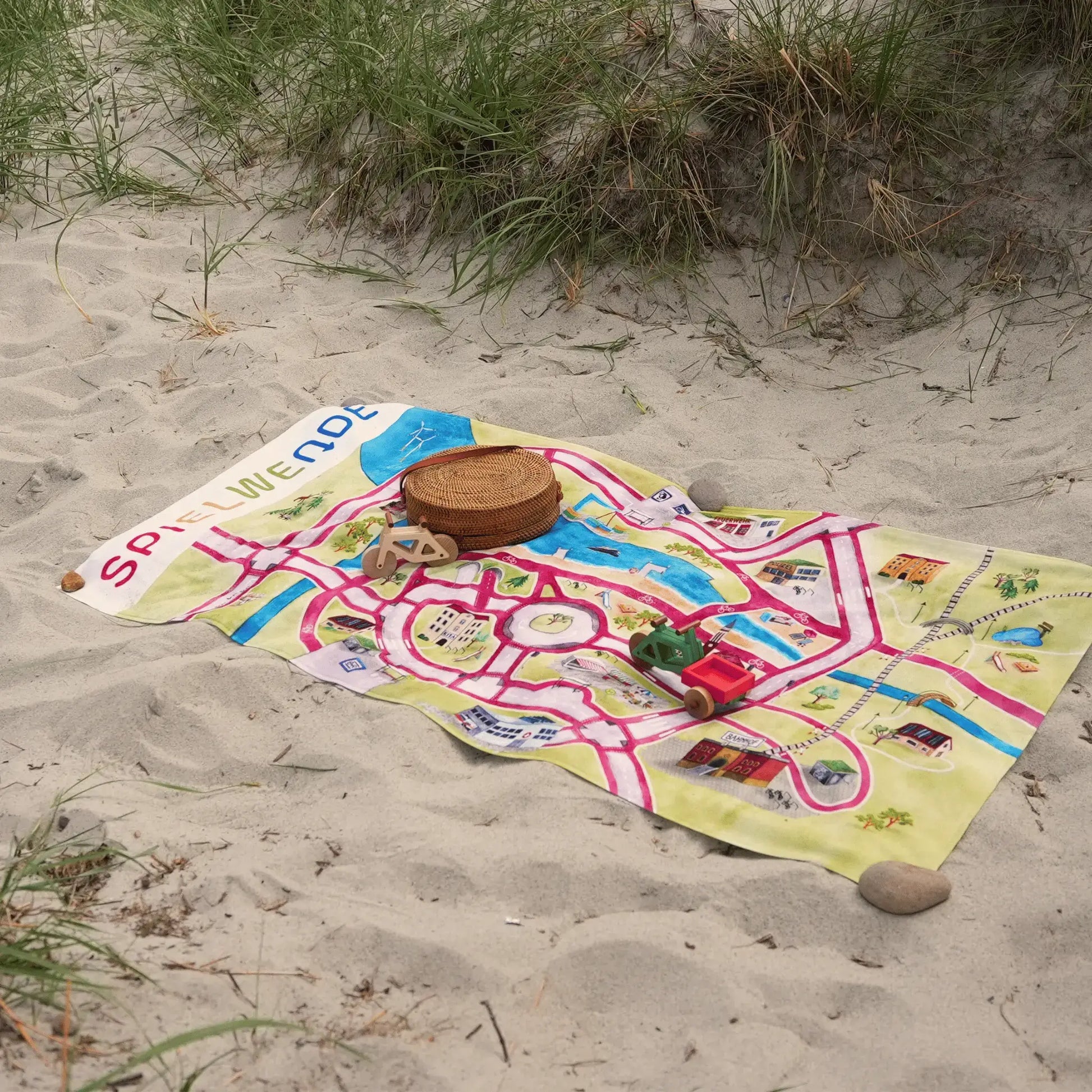 Strandhandtuch 'Stadt von Morgen' 140x70cm, farbenfrohes Design mit nachhaltigen Stadtmotiven, liegt auf dem Strand.
