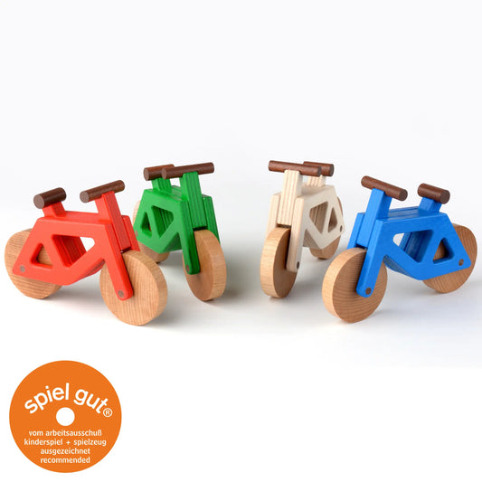 Spielzeugfahrräder aus Holz in den Farben rot, grün, natur und blau