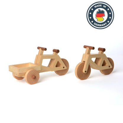 Das Spielzeug-Lastenrad und Spielzeugfahrrad in natur stehen nebeneinander. Rechts oben ein Siegel "Made in Germany".